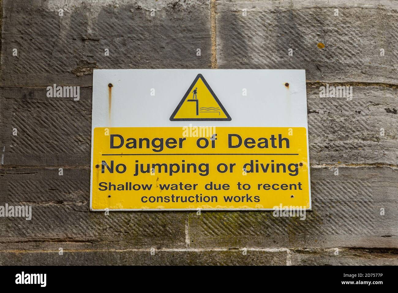 Un panneau sur un mur près de la mer avertissement de les dangers de sauter dans la mer et que là est un danger de mort Banque D'Images