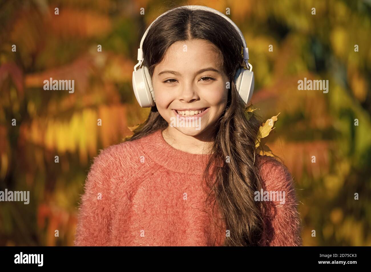 Pour l'éducation et à télécharger des livres audio pour les enfants. Kid girl relaxing près de l'arbre d'automne avec le casque. La musique pour l'humeur d'automne. Chanson d'écoute. Profitez de la musique jour d'automne. Promenades d'automne avec de belles chansons. Banque D'Images