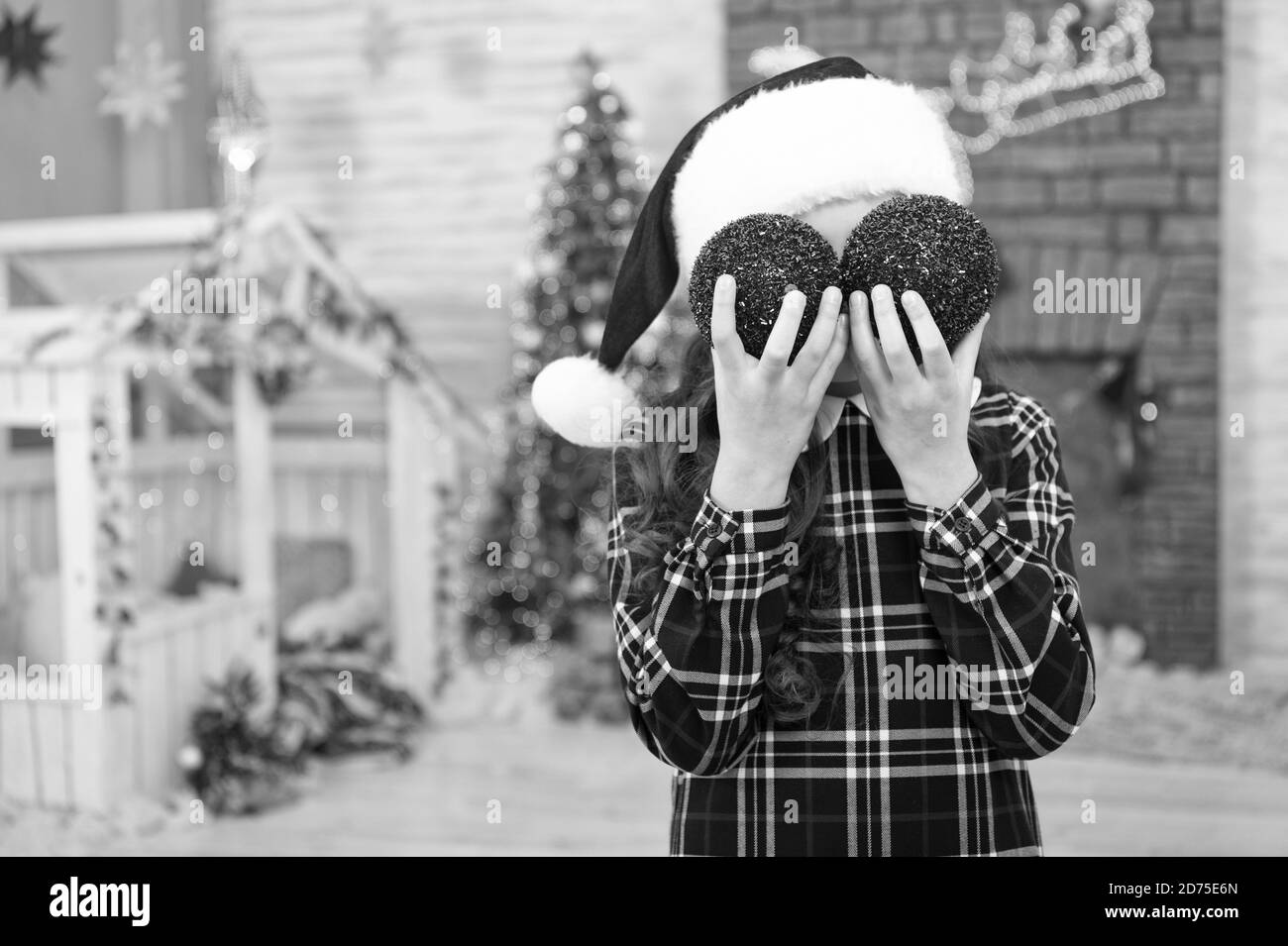 Enfant espiègle. Kid santa hat near christmas tree. La décoration de son activité favorite. Boutique de décoration. Accueil décorations de sélection. Enfant decorating Christmas Tree balls. Kid Girl decorating Christmas Tree. Banque D'Images