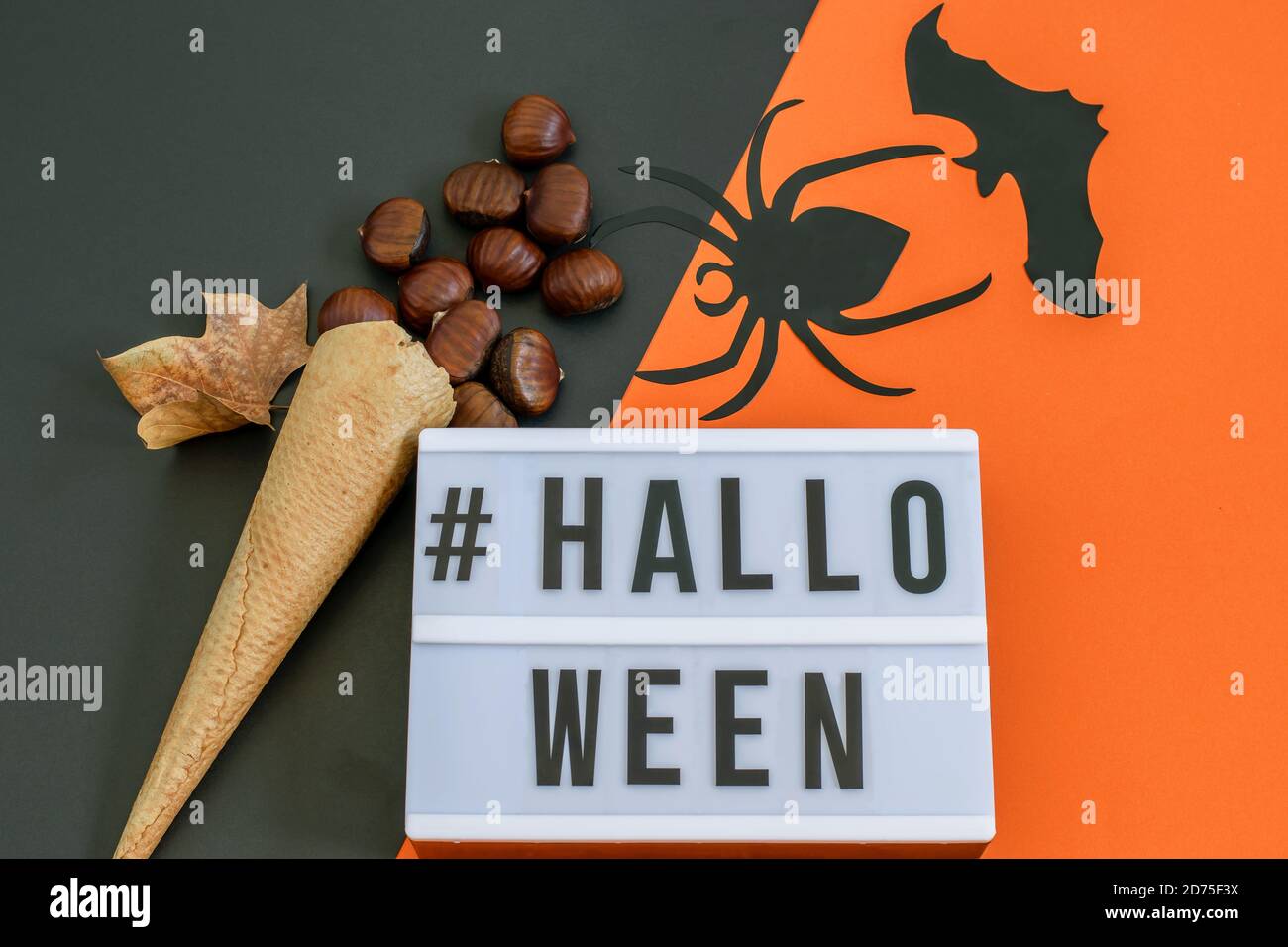 Texte Halloween sur fond noir-orange, gaufre glace cône avec châtaignes et chauve-souris décorative et araignée. Carte de vœux ou invitation à une fête Banque D'Images