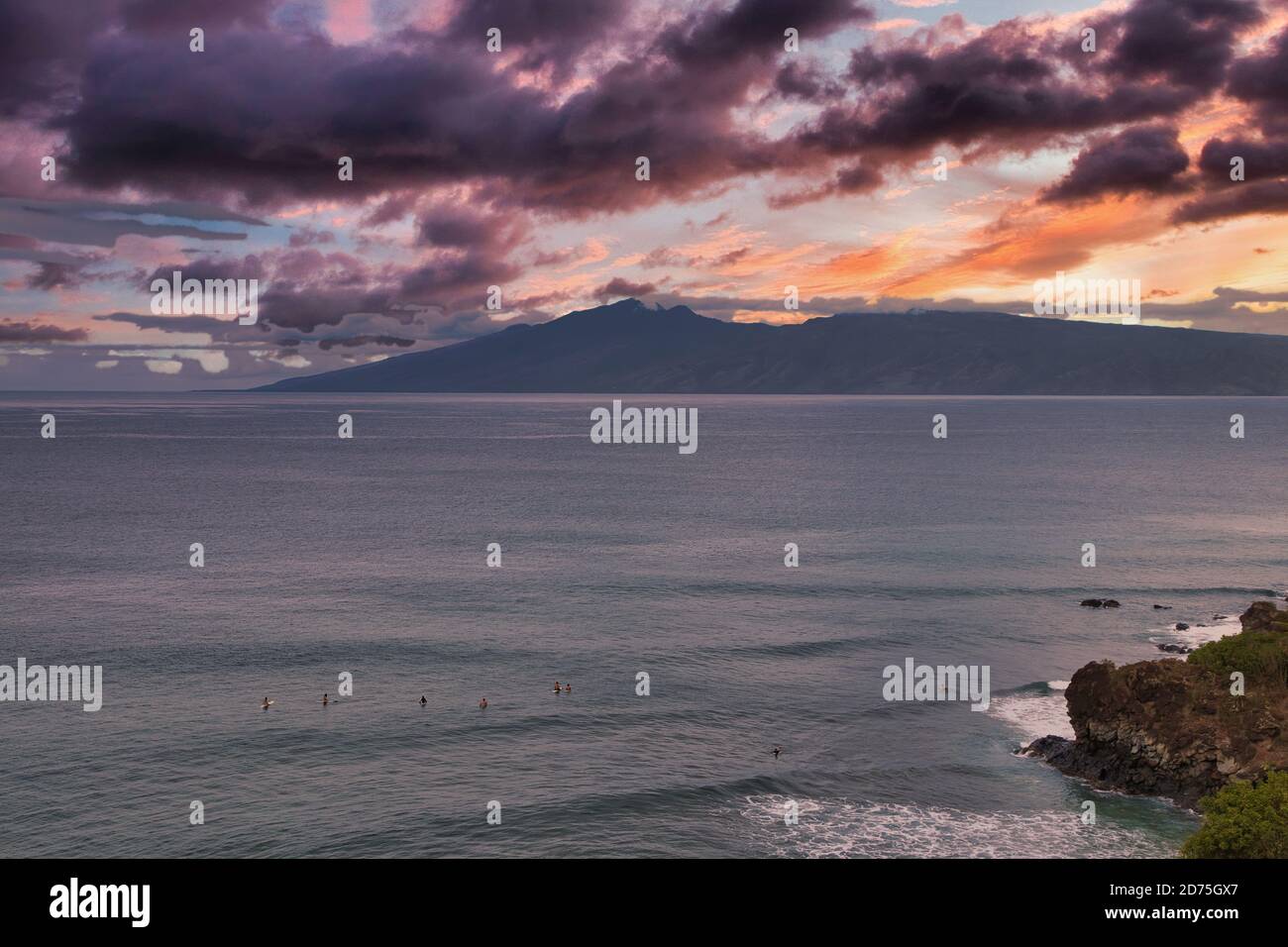 Surfeurs assis sur leurs planches à la baie de la baie de la ville de Maui au coucher du soleil. Banque D'Images