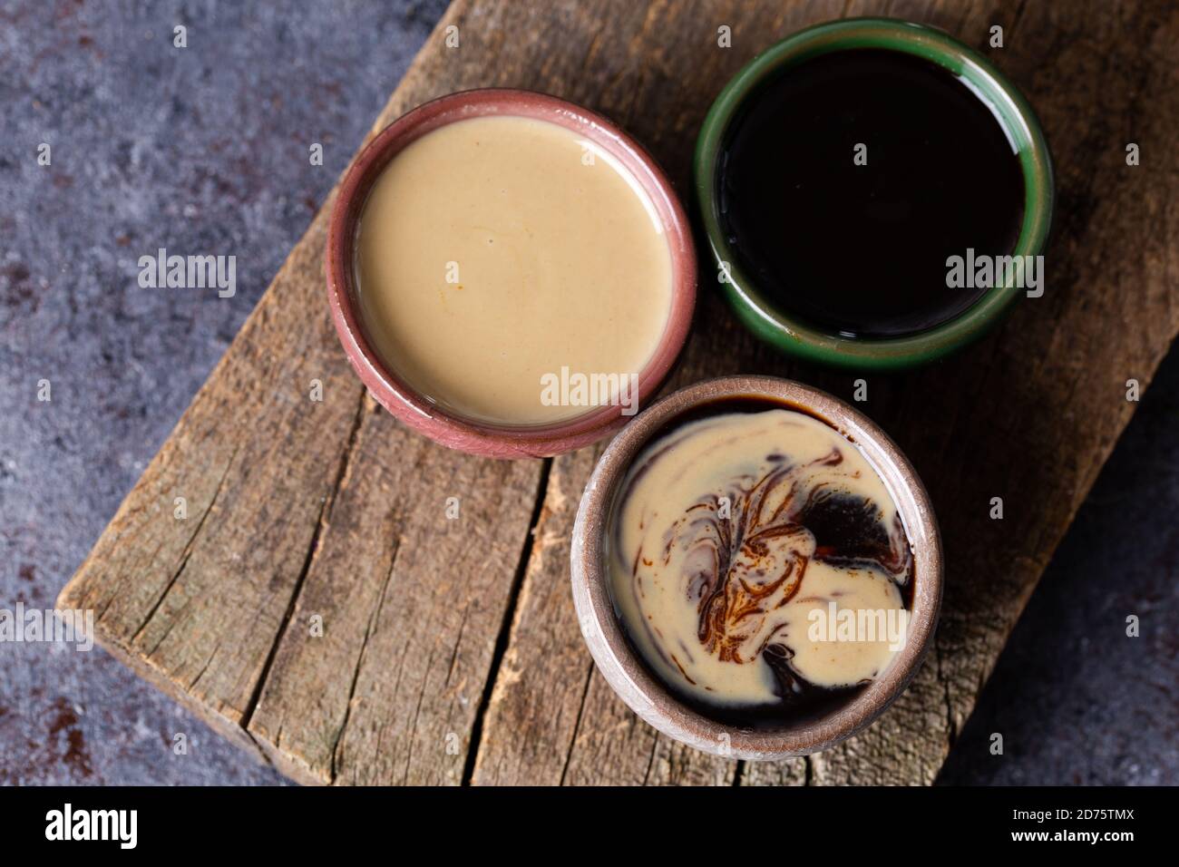 Tahini et mélasse / tahin turc Pekmez sur bois. Tahini et mélasses mélangés dans un bol. Banque D'Images