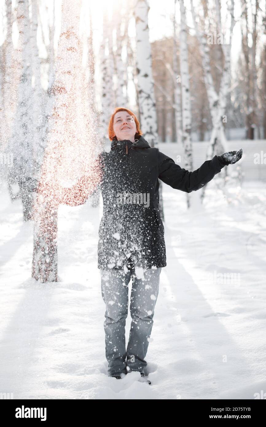 Fille en forêt d'hiver entourée de flocons de neige. Banque D'Images