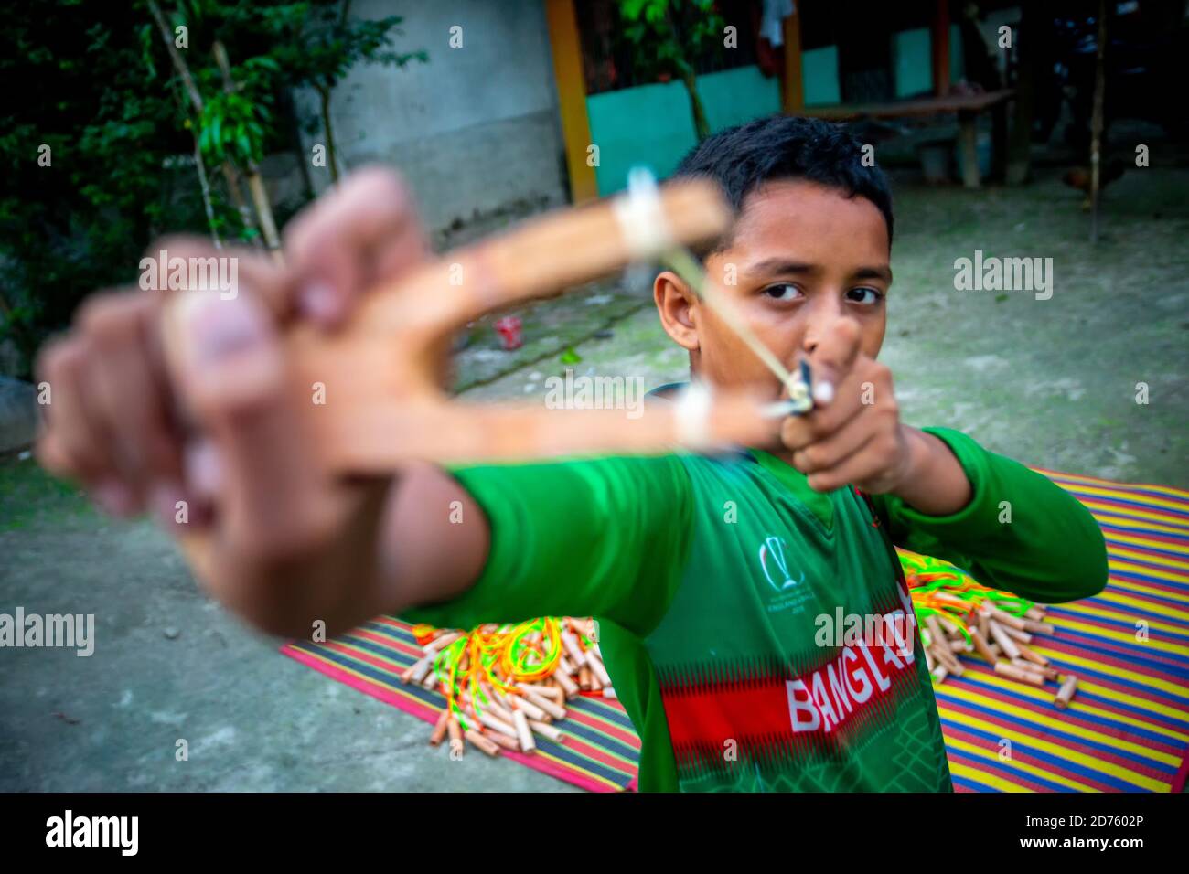Bangladesh – 04 octobre 2020 : un gamin de cricket du Bangladesh portant un maillot de cricket qui tira un coup de feu en bois à Barinagar, Jessore. Banque D'Images