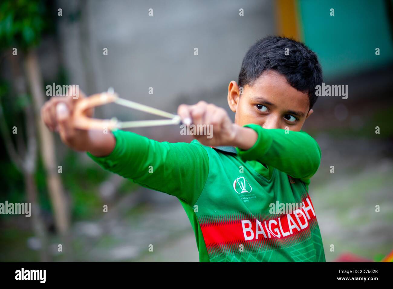 Bangladesh – 04 octobre 2020 : un gamin de cricket du Bangladesh portant un maillot de cricket qui tira un coup de feu en bois à Barinagar, Jessore. Banque D'Images