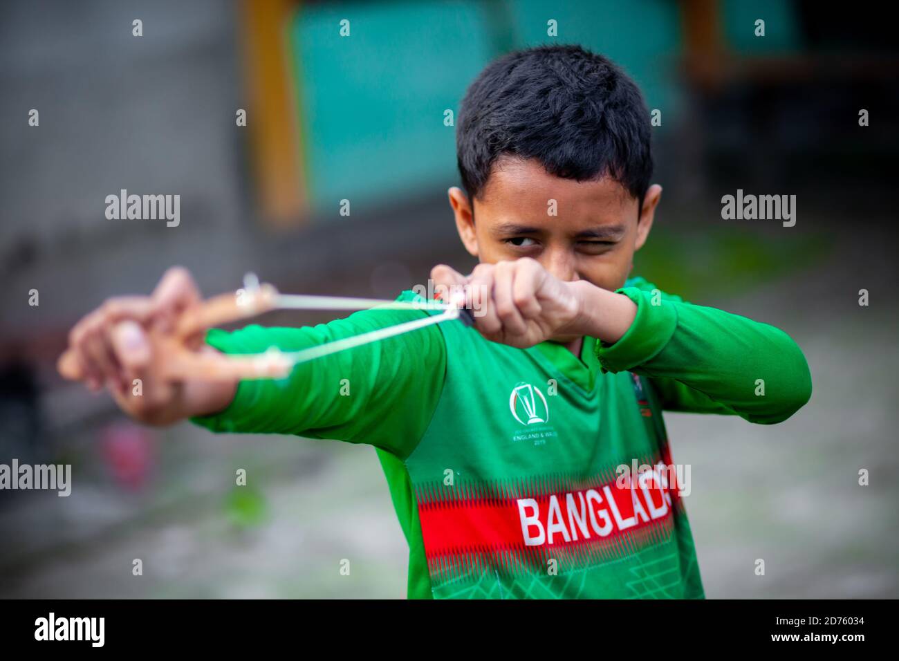 Bangladesh – 04 octobre 2020 : un gamin de cricket du Bangladesh portant un maillot de cricket qui tira un coup de feu en bois à Barinagar, Jessore. Banque D'Images