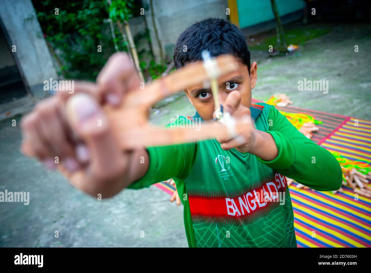 Bangladesh – 04 octobre 2020 : un gamin de cricket du Bangladesh portant un maillot de cricket qui tira un coup de feu en bois à Barinagar, Jessore. Banque D'Images