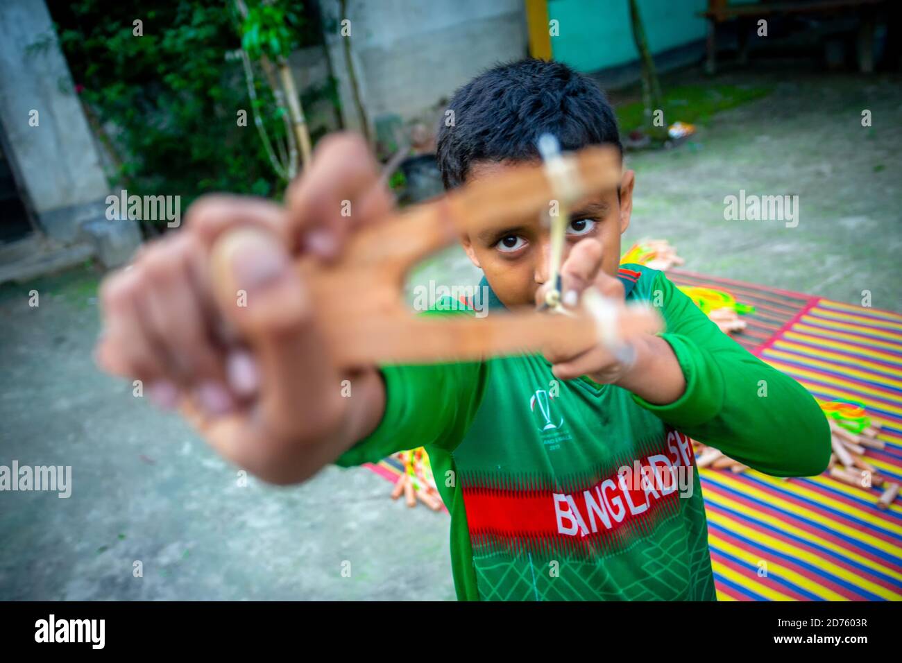 Bangladesh – 04 octobre 2020 : un gamin de cricket du Bangladesh portant un maillot de cricket qui tira un coup de feu en bois à Barinagar, Jessore. Banque D'Images