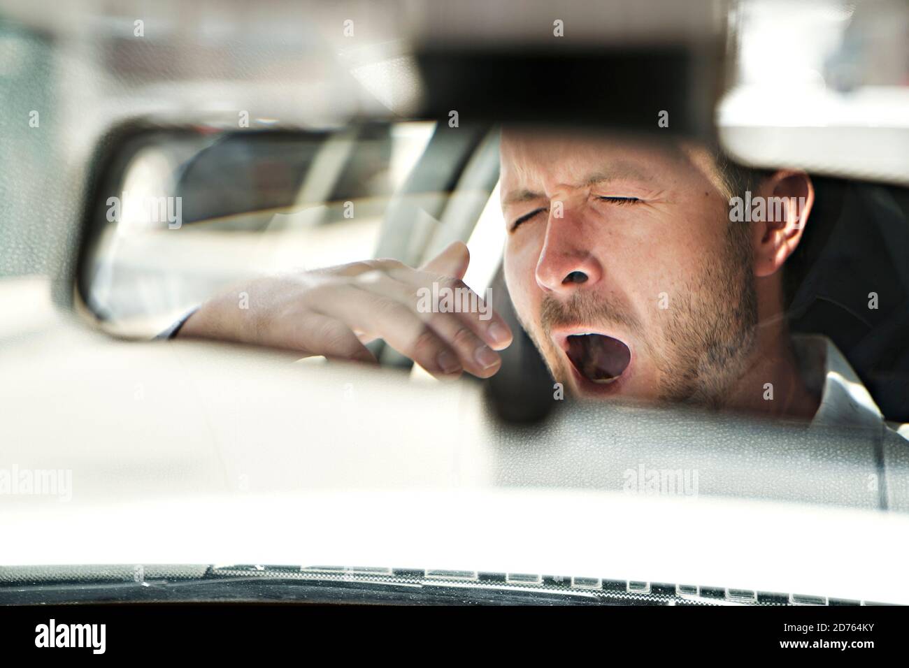 l'homme bâille dans sa voiture parce qu'il est si fatigué Banque D'Images