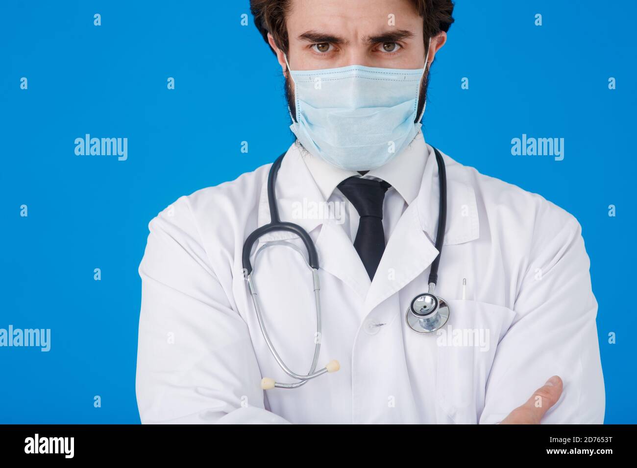 Médecin sous un manteau blanc et un masque médical, avec un endoscope autour de son cou de près - sur un fond bleu. Concept de protection contre les virus et Banque D'Images