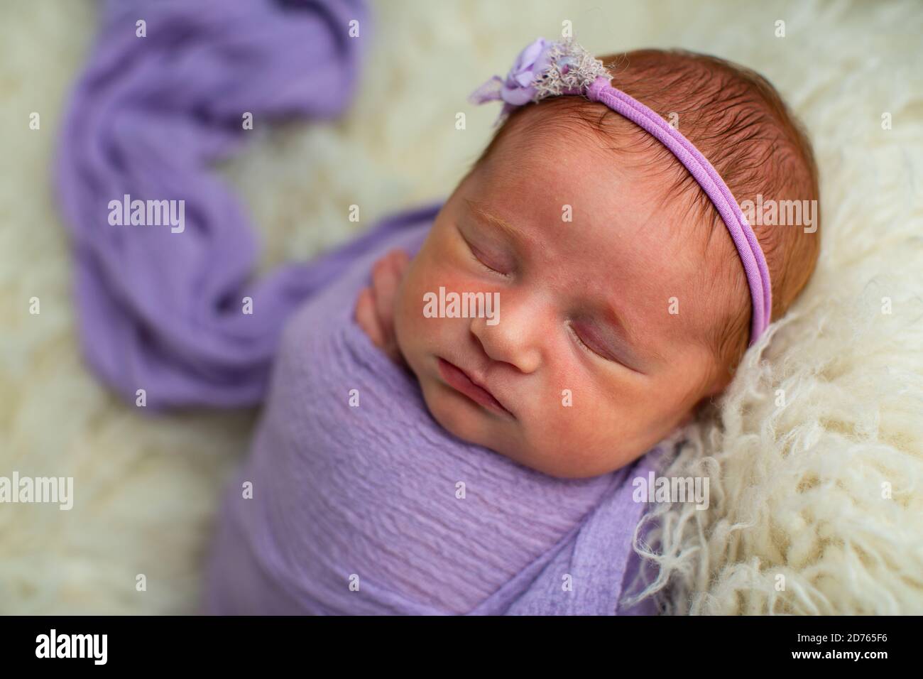 Dormant, bébé fille de neuf jours de nouveau-né dans un emballage violet Banque D'Images