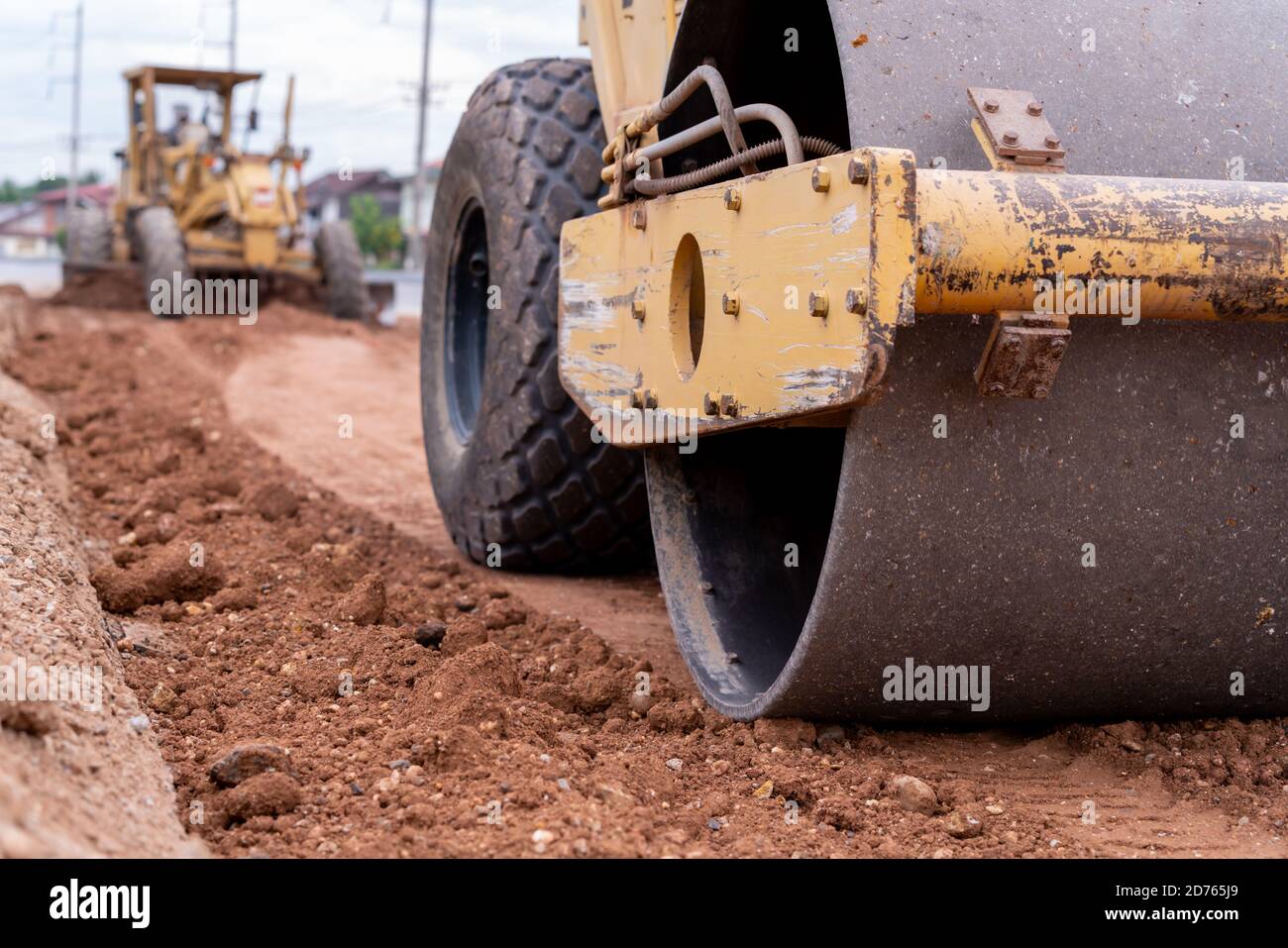 Gros plan Compacteur de sol vibrant jaune et niveleuse compacteur de sol civil travaillant sur un chantier de construction de routes, compacteur de sol vibrant jaune en construction de routes Banque D'Images