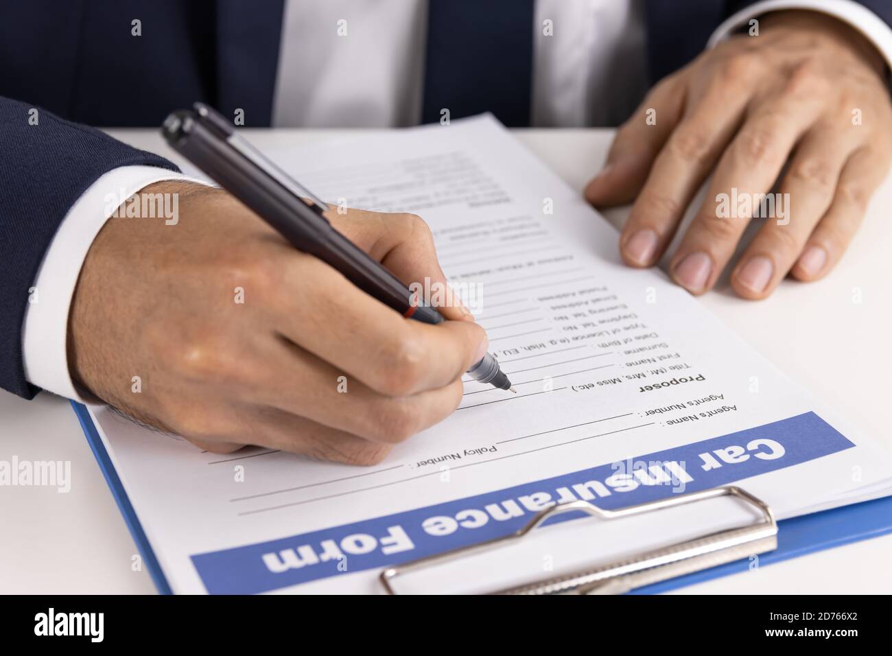 L'agent d'assurance Zoom écrit à la main le formulaire de demande de remboursement d'assurance automobile ou Document d'assurance sur la vue latérale de la table de bureau Banque D'Images