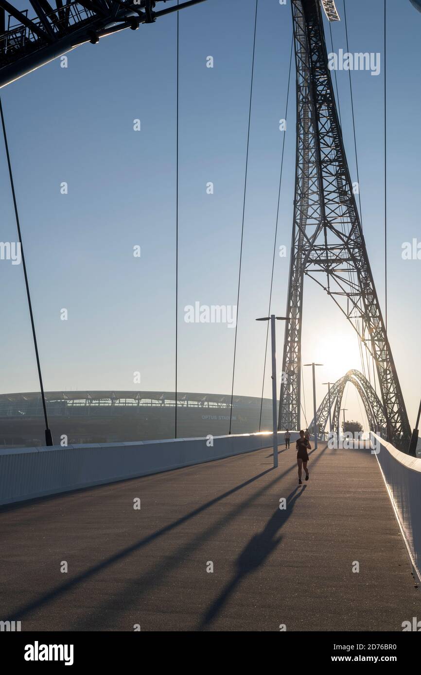 Jogger sur le pont Matagarup, traversant la rivière Swan, au lever du soleil. Banque D'Images
