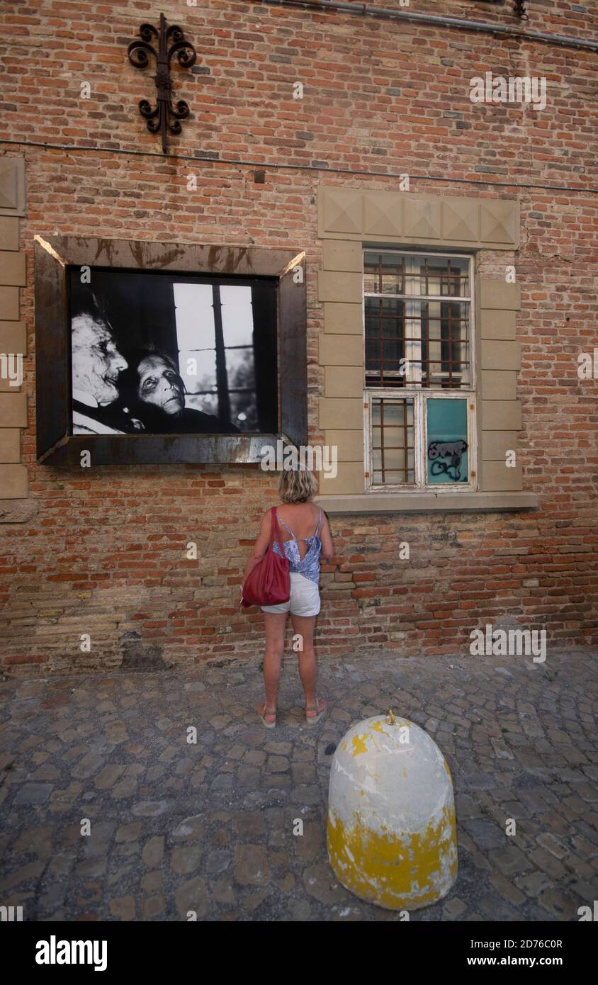 Un touriste observe l'un des magnifiques noirs et blancs de Giacomelli Photos affichées le long des rues de Mondolfo Banque D'Images