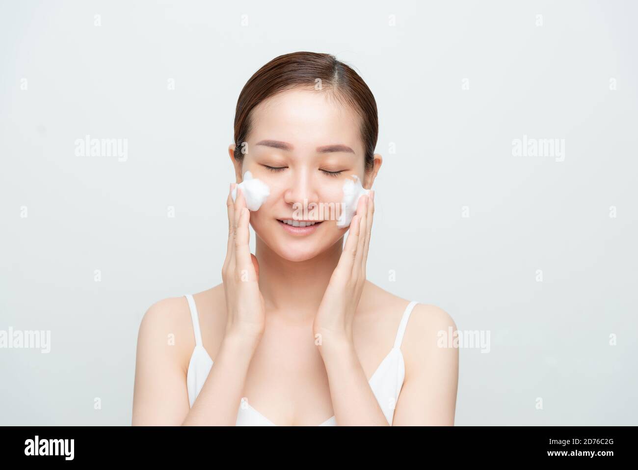 Portrait de la femme joyeuse qui rit en appliquant de la mousse pour se laver sur son visage. Banque D'Images