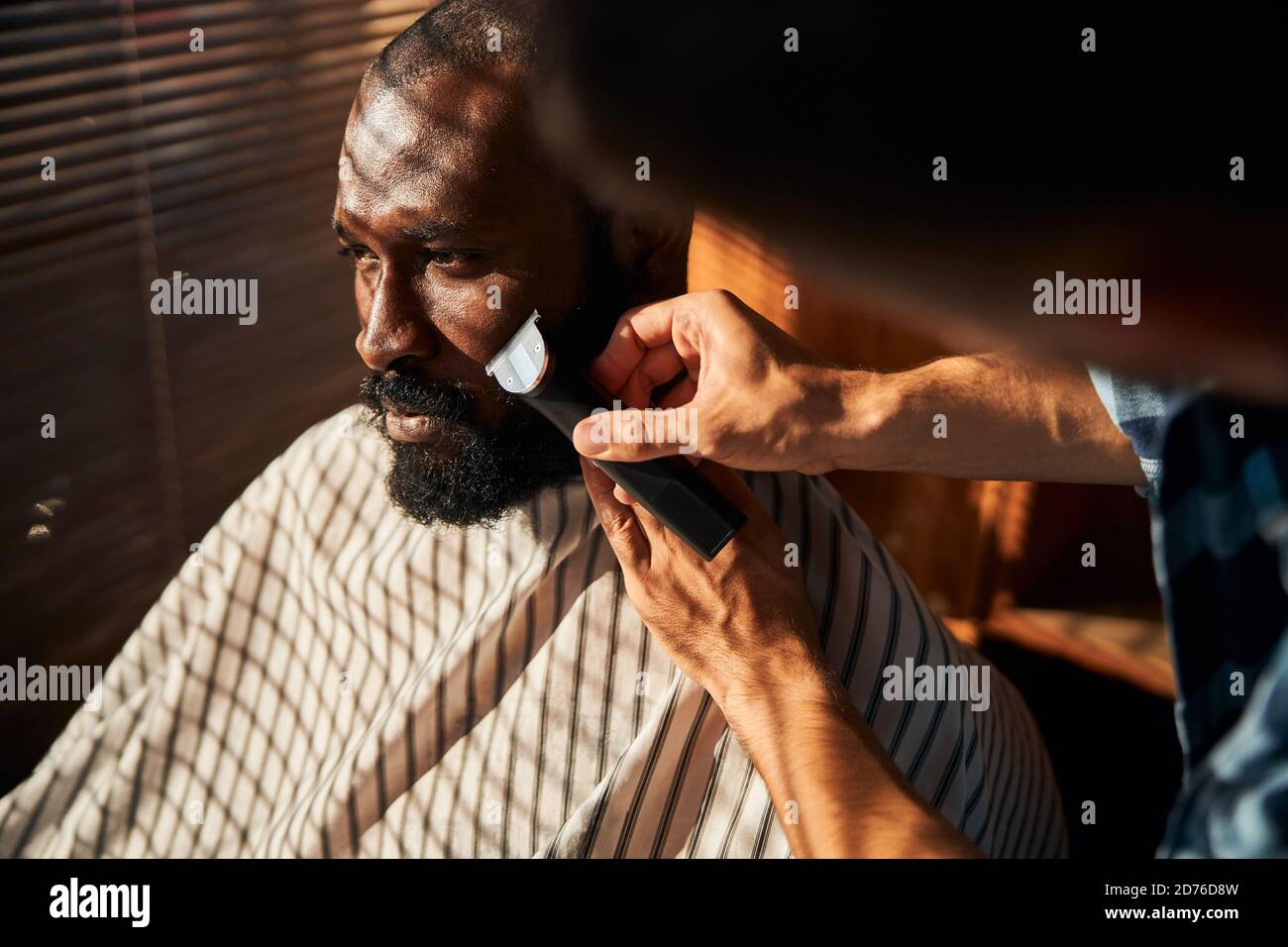 Barbe rasage de la barbe du client avec tondeuse électrique dans un salon de coiffure Banque D'Images