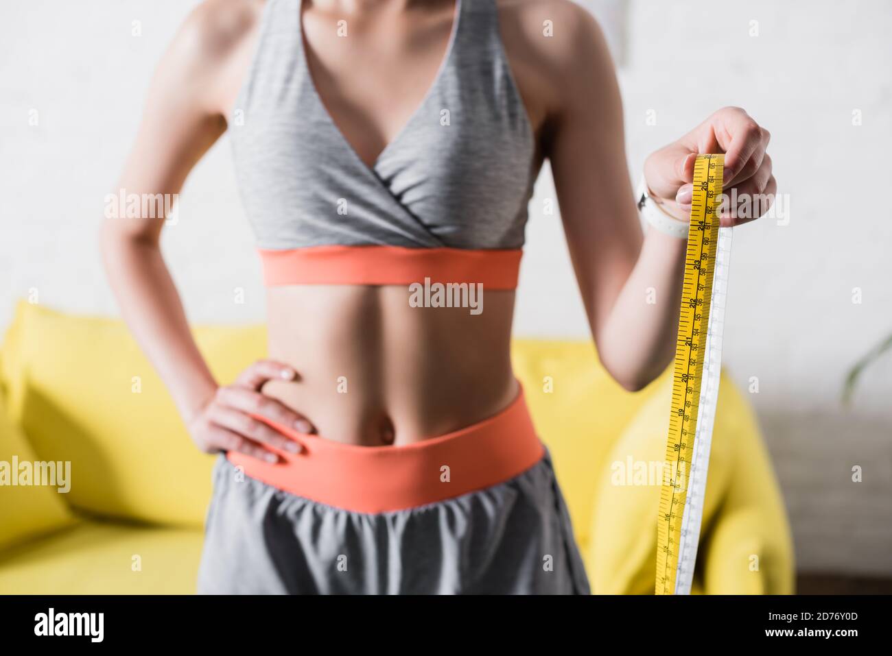 Vue rognée de la sportswoman avec mesure de la main sur la hanche à la maison Banque D'Images