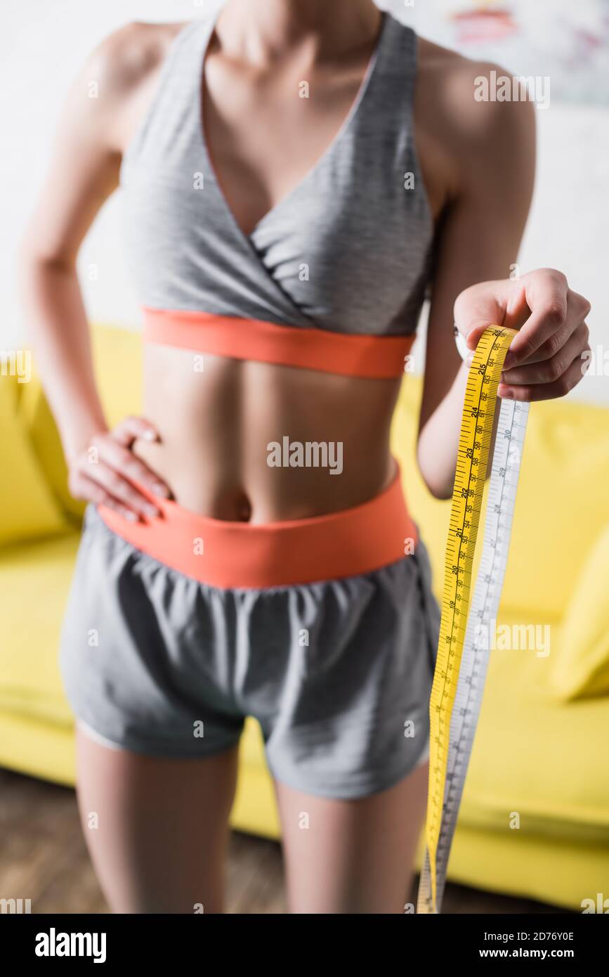 Vue rognée de la sportswoman avec mesure de la main sur la hanche à la maison Banque D'Images