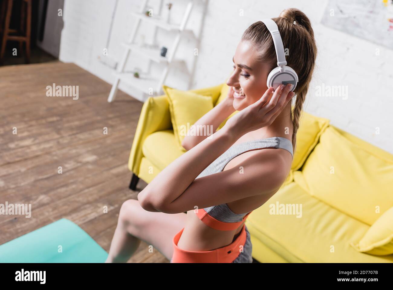 Bonne sportswoman écoutant de la musique dans un casque pendant votre entraînement à la maison Banque D'Images