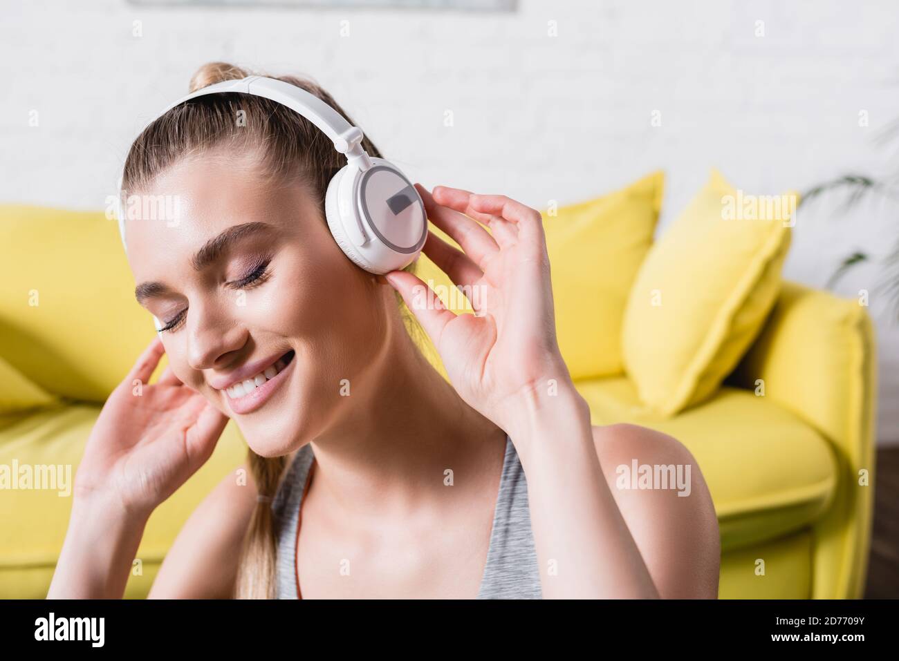 Femme souriante aux yeux fermés, écoutant de la musique dans un casque à accueil Banque D'Images