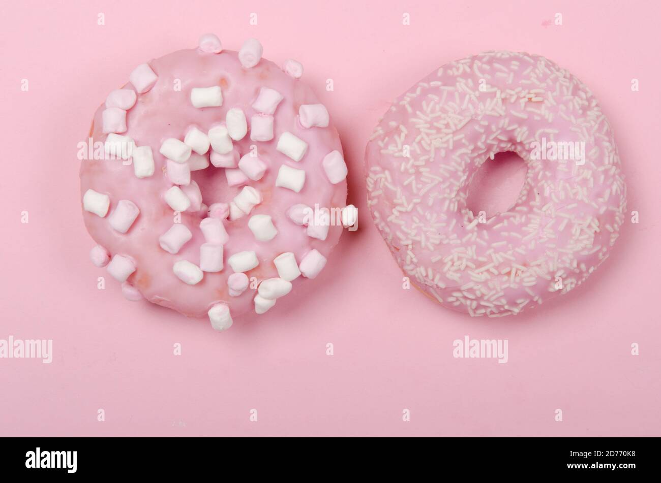 Deux beignets avec glaçage sur fond rose pastel. Beignets sucrés. CopySpace Banque D'Images