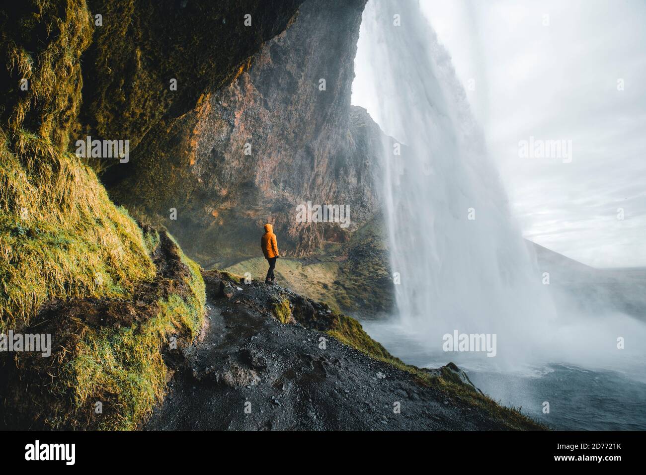 Homme aventureux debout sous la cascade, la chute d'eau Seljalandsfoss dans la partie sud de l'Islande Banque D'Images