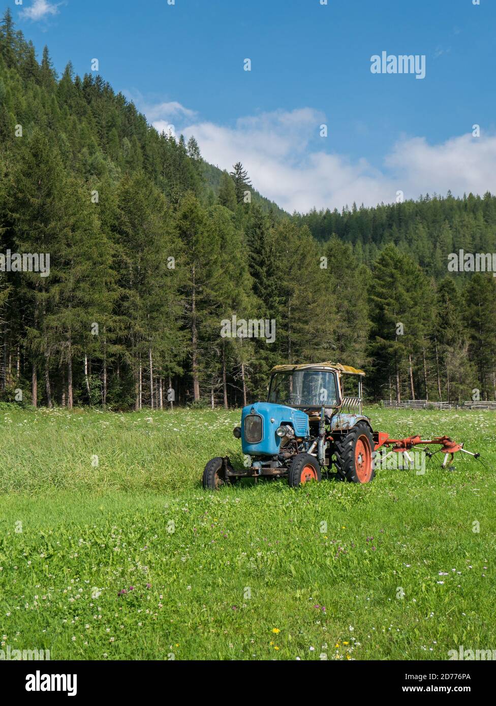 Tracteur d'époque sur un pré vert en face d'une forêt de montagne. Scène près de Längenfeld, Tyrol, Autriche Banque D'Images