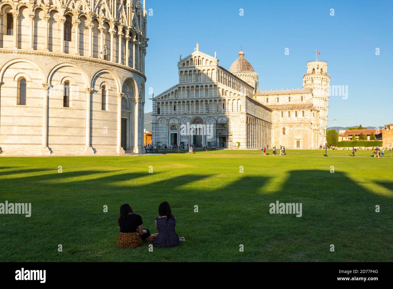 Les touristes s'assoient sur l'herbe en face du Baptistère de San Giovanni à Pise, Toscane, Italie Banque D'Images