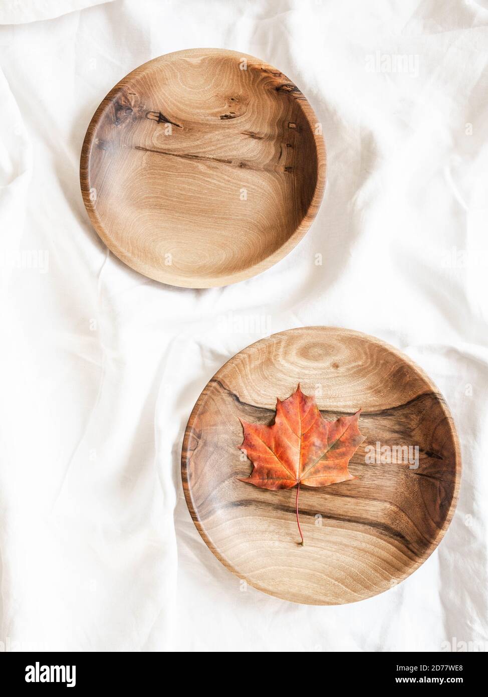 Vue de dessus d'un bol en bois rond brun vide fait à la main et d'un bol avec feuille d'automne rouge sur une nappe en coton blanc. Mise en page à plat. Sapce copie Banque D'Images