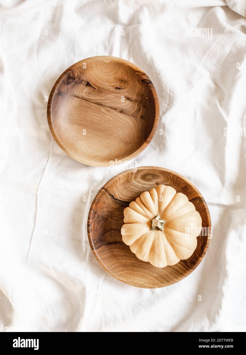 Vue de dessus d'un bol en bois rond brun vide fait à la main et d'un bol avec potiron sur une nappe en coton blanc. Espace de copie de la mise à plat Banque D'Images