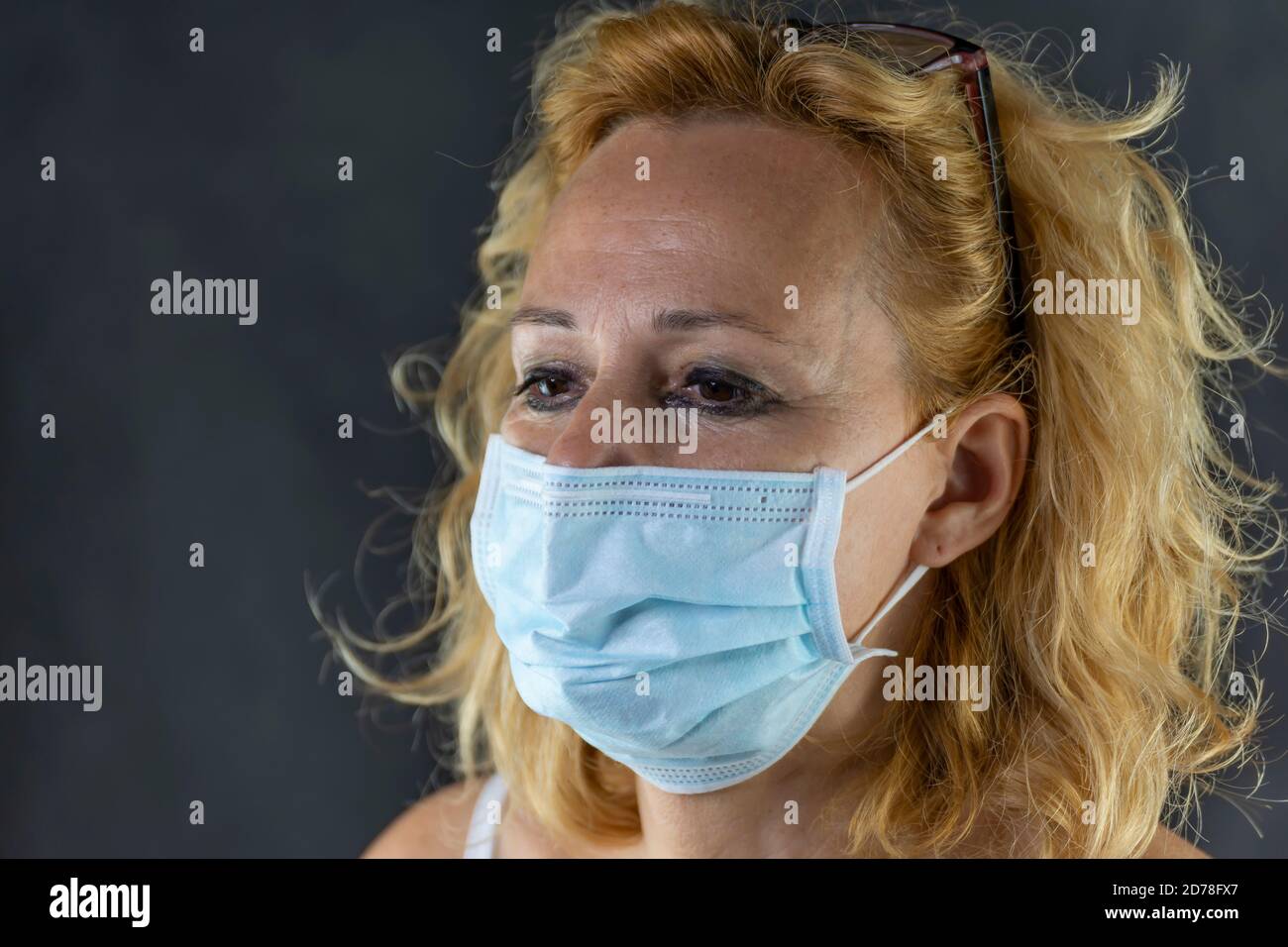 Portrait d'une femme blanche d'âge moyen qui pleure, forcée de porter un masque protecteur contre le risque de contagion du coronavirus Covid-19 Banque D'Images