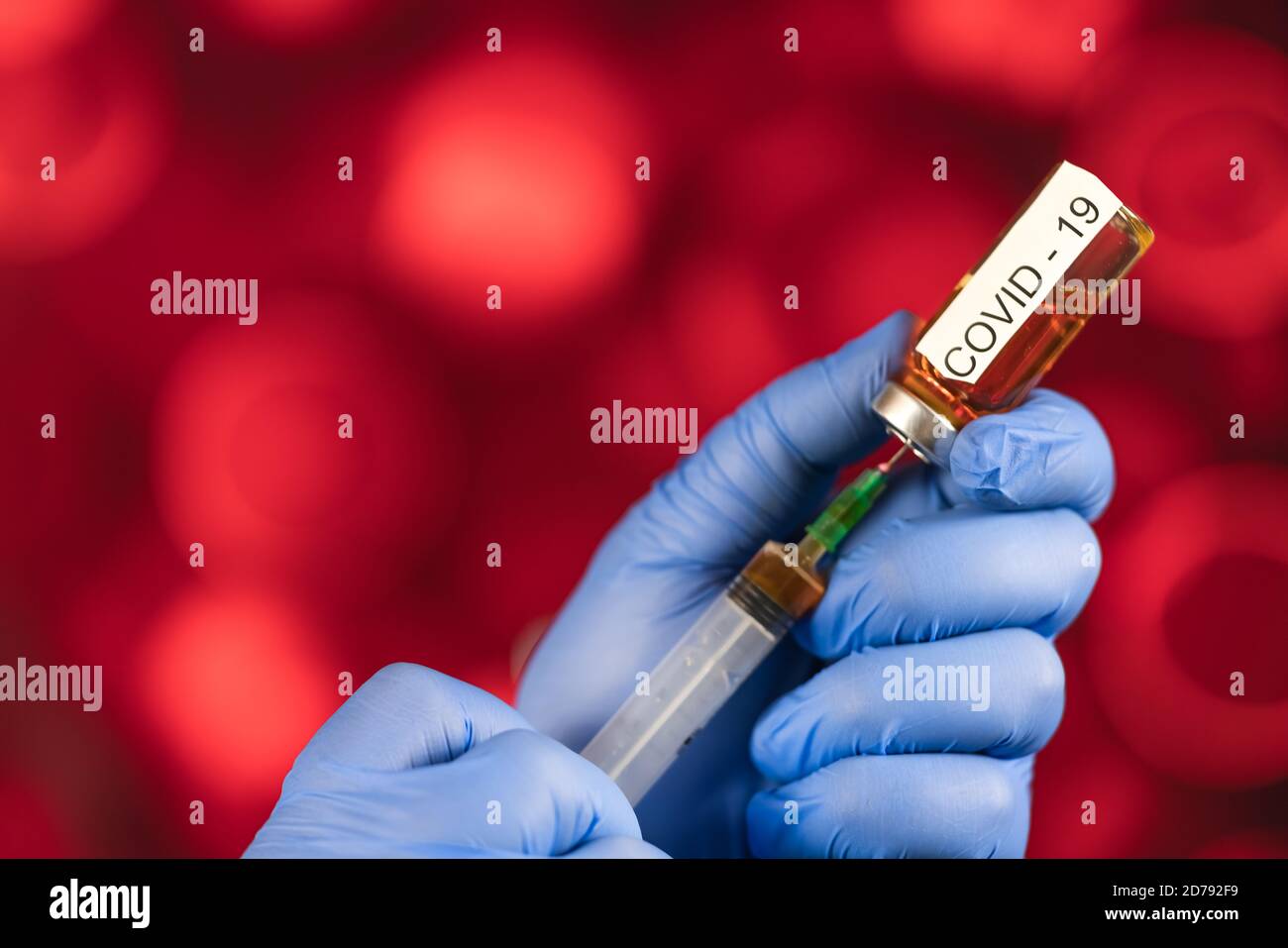 Un professionnel de la santé aux gants bleus aspire une ampoule dans une seringue. Vaccin médical contre la grippe coronavirus concept. Flacon d'injection pour verre médical Banque D'Images