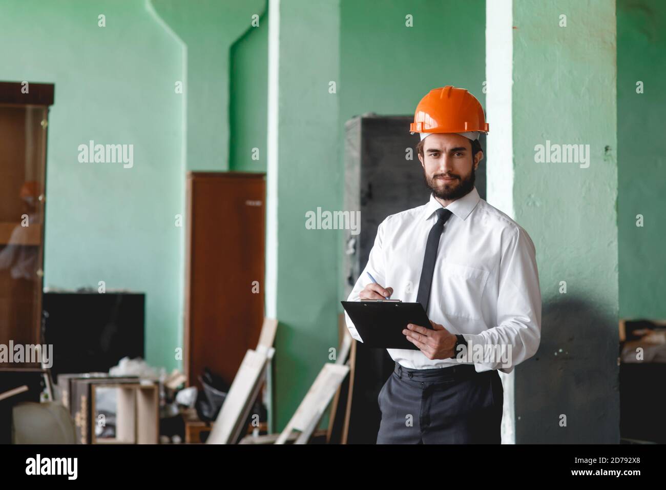 Un jeune architecte barbu dans un casque de construction sur un le chantier vérifie le résultat Banque D'Images
