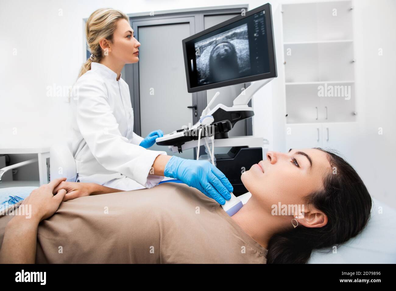 Femme endocrinologue qui effectue l'échographie à une patiente dans un bureau d'échographie. Diagnostic échographique de la glande thyroïde. Banque D'Images