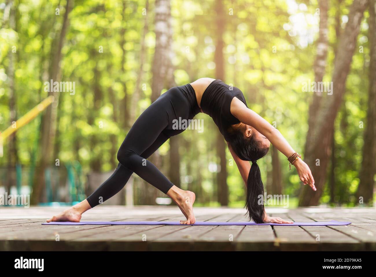 Une jeune femme en vêtements de sport noirs fait de l'exercice de yoga Banque D'Images