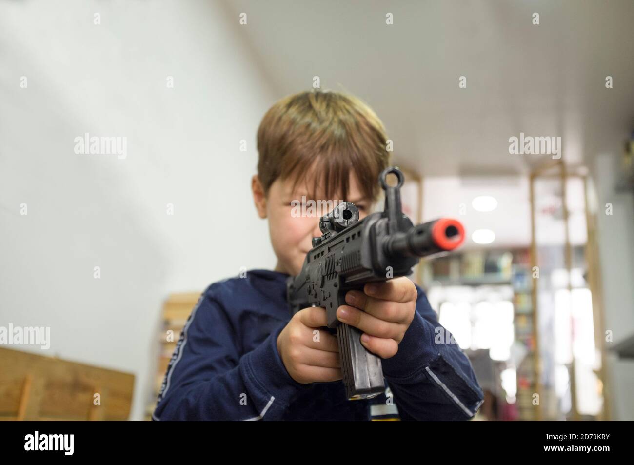 5 ans petit garçon jouant avec le fusil d'assaut. Concept de pistolets de jouets. Mise au point sélective Banque D'Images