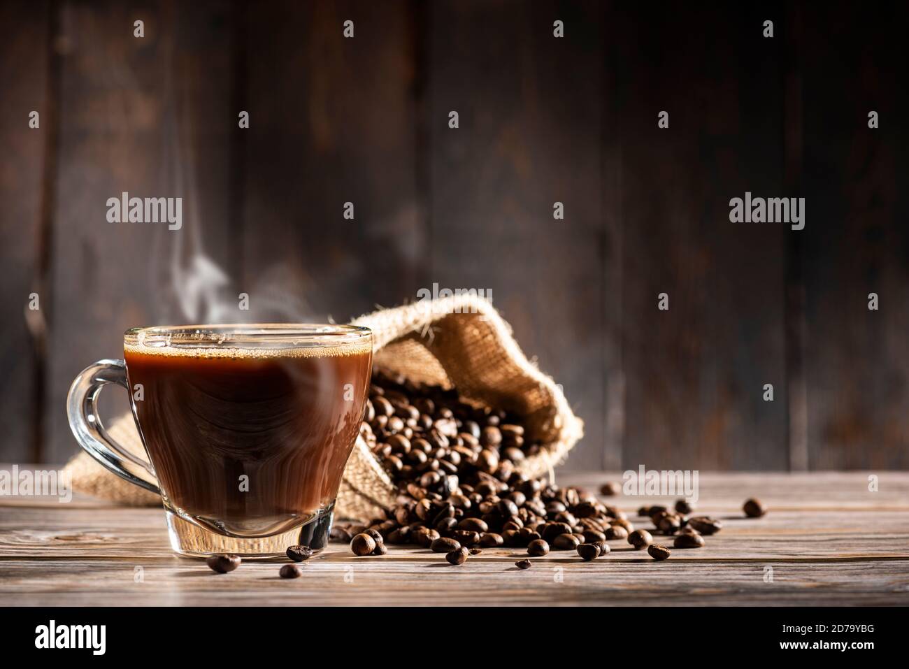 tasse en verre pleine de café cuit à la vapeur sur fond de bois avec grains de café Banque D'Images