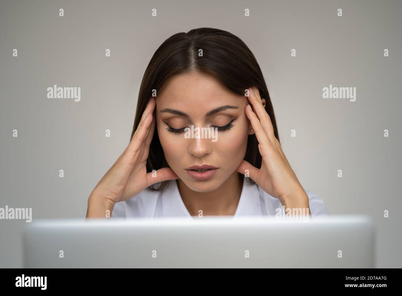 Femme d'affaires se sentant mal de tête, massant les temples, fatigué, épuisé de travail excessif au bureau sur le mur gris, gros plan. Fatigue débordée de l'employé su Banque D'Images