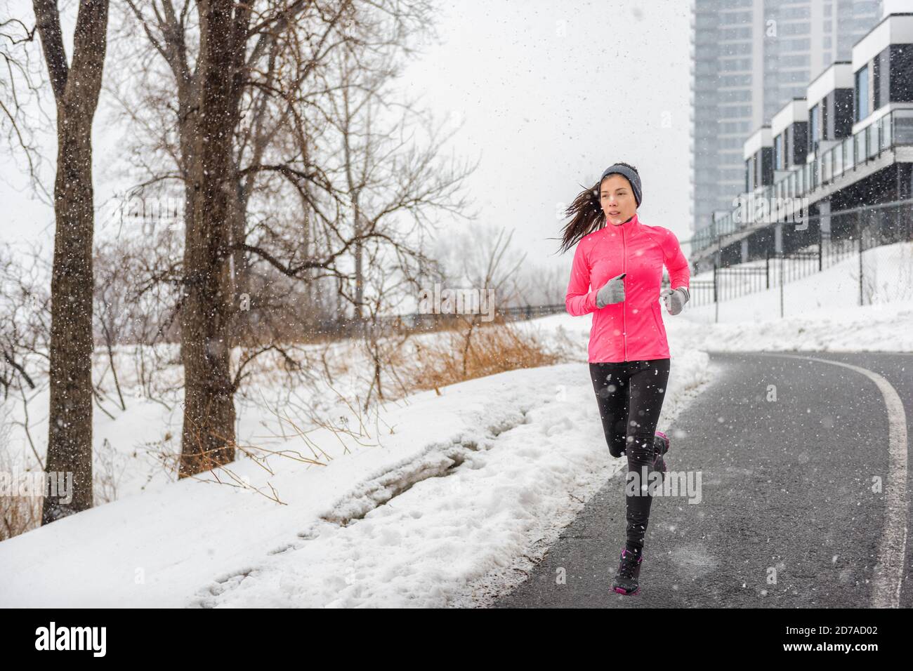 Hiver running asiatique fille portant des vêtements temps froid pour l'extérieur exercice dans la tempête de neige chute de neige pendant l'entraînement d'hiver à l'extérieur rue de la ville Banque D'Images