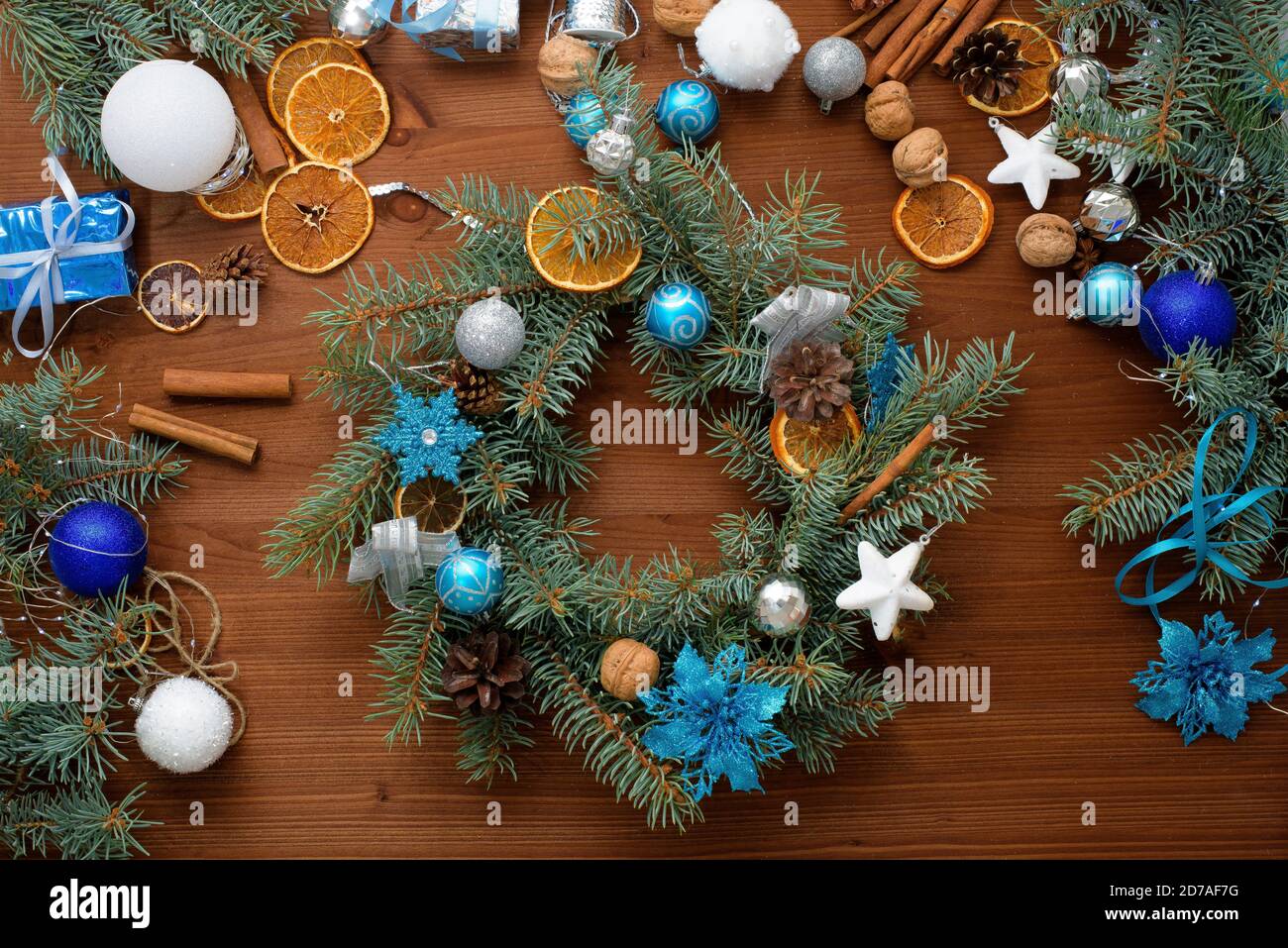 Processus étape par étape de fabrication d'une couronne d'arbre de Noël à la maison à partir de branches d'épinette, d'oranges et de boules de Noël dans les couleurs argent et bleu de la Banque D'Images