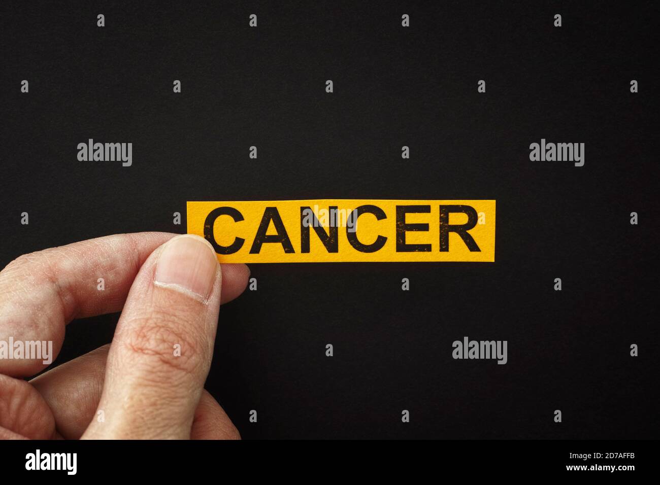 Homme tenant un morceau de papier jaune avec le mot cancer dans sa main. Gros plan. Banque D'Images Homme tenant un morceau de papier jaune avec le mot cancer dans sa main. Gros plan. Banque D'Images