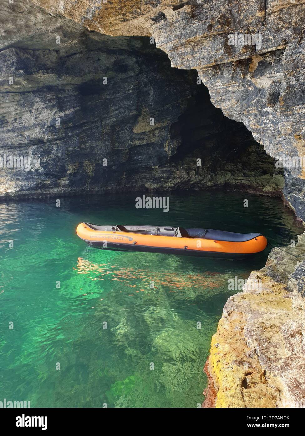 Plan vertical d'un bateau gonflable dans la mer avec falaises en arrière-plan Banque D'Images