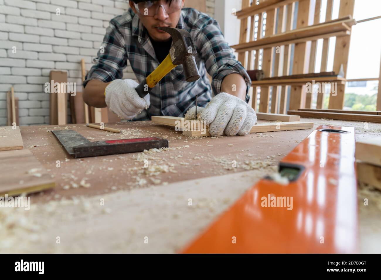 Charpenter travaillant sur l'artisanat en bois à l'atelier pour produire du matériel de construction ou des meubles en bois. Le jeune menuisier asiatique utilise des outils professionnels pour Banque D'Images