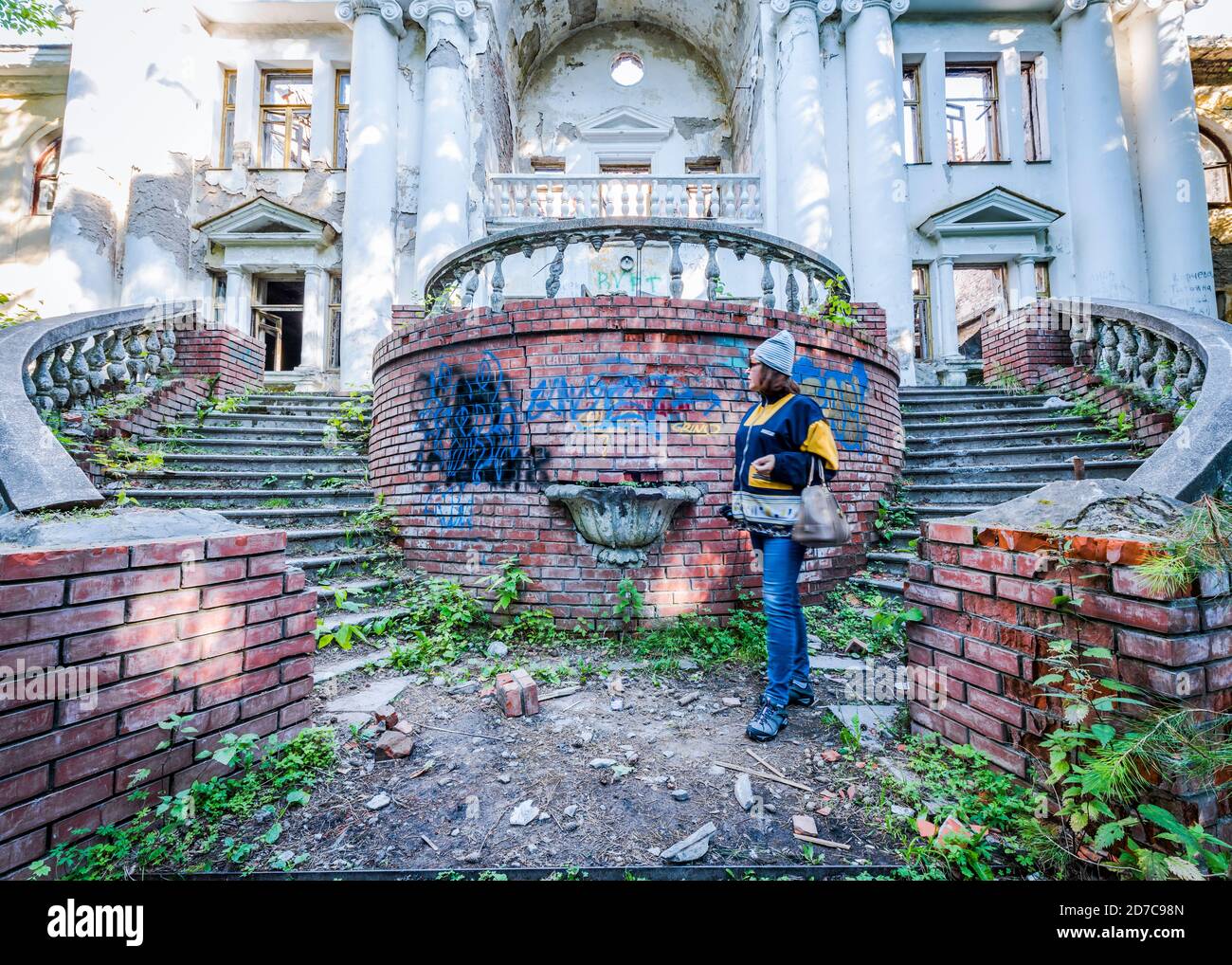 BERDSK, RUSSIE - 4 AOÛT 2018 : une femme marche près d'un bâtiment abandonné en délabrement dans le vieux parc. Escaliers, colonnes et balustrade. Seul le f Banque D'Images