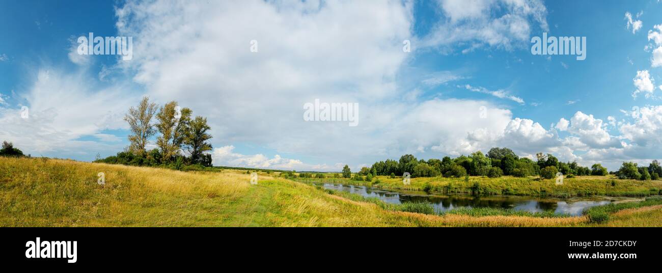 Paysage rural ensoleillé d'été avec rivière calme, route de campagne et doré champs de ferme Banque D'Images