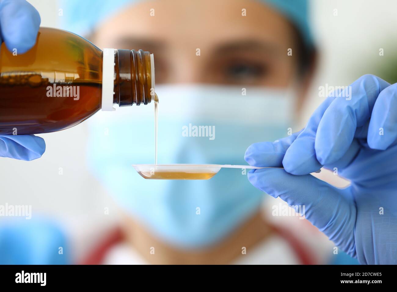 Le médecin tient le sirop et le verse dans une cuillère Banque D'Images