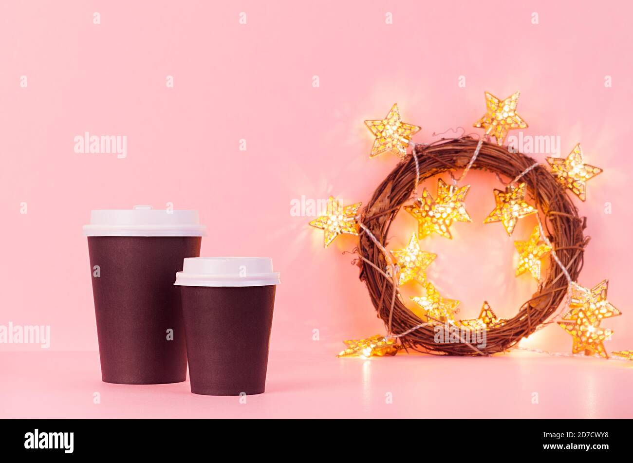Maquette de tasses en papier de café noir avec des lumières dorées de noël dans une couronne sur fond rose, modèle pour la publicité, le design, le café, le restaurant Banque D'Images Maquette de tasses en papier de café noir avec des lumières dorées de noël dans une couronne sur fond rose, modèle pour la publicité, le design, le café, le restaurant Banque D'Images