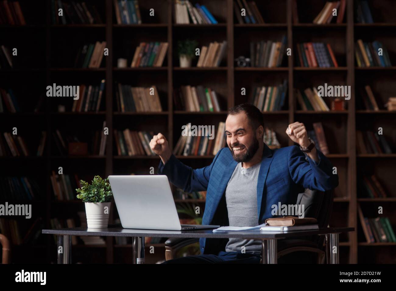 Un jeune homme d'affaires plein de joie et de joie à l'occasion de la fête des PC portables BID gagner en ligne succès gagner une nouvelle occasion de s'asseoir au bureau Banque D'Images
