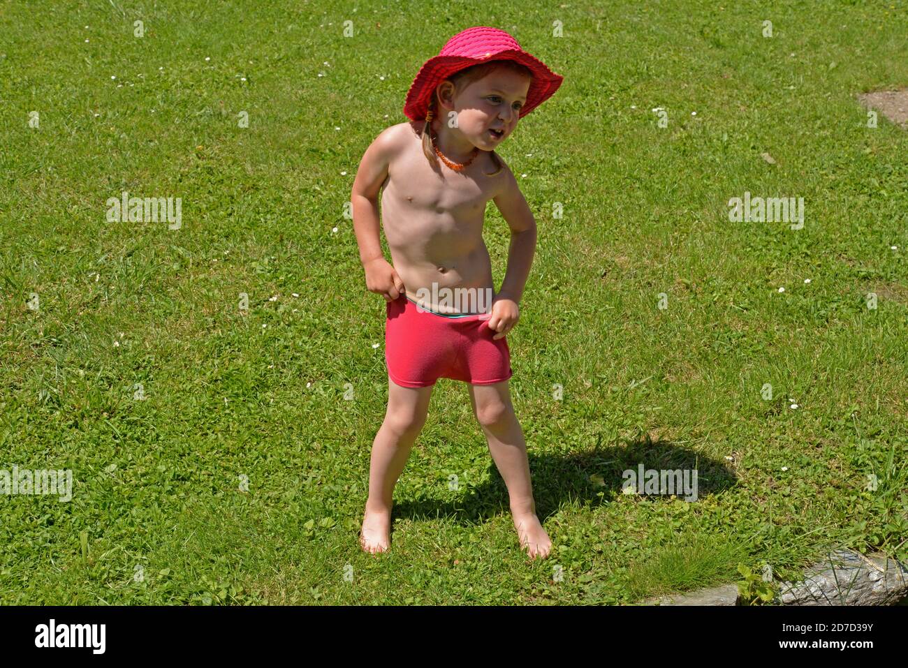 Mouillez la petite fille après avoir joué avec le jet d'eau dedans maillot de bain Banque D'Images